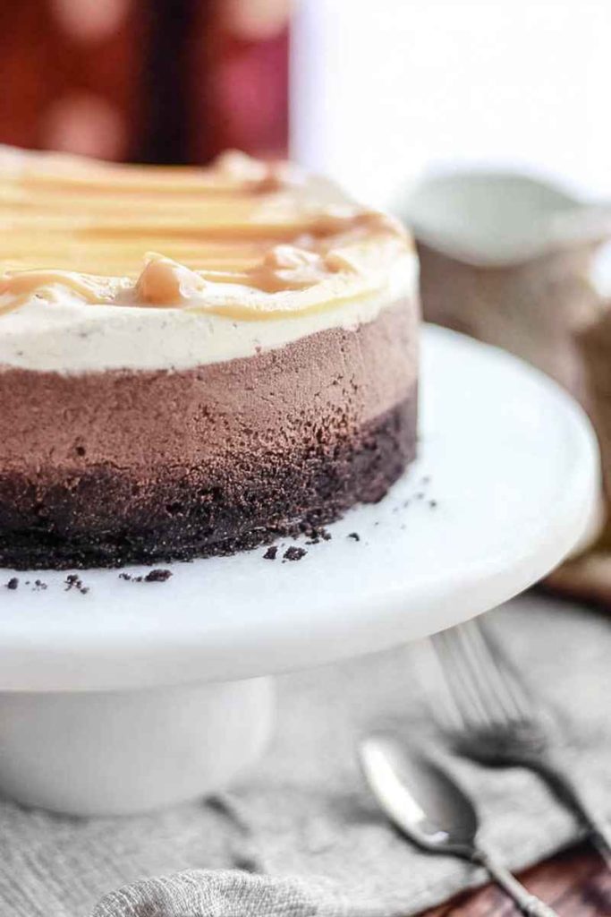A whole Caramel Hot Chocolate Brownie Mousse Cake with layers of brownie crust, hot chocolate mousse, caramel whipped cream, and caramel drizzle.