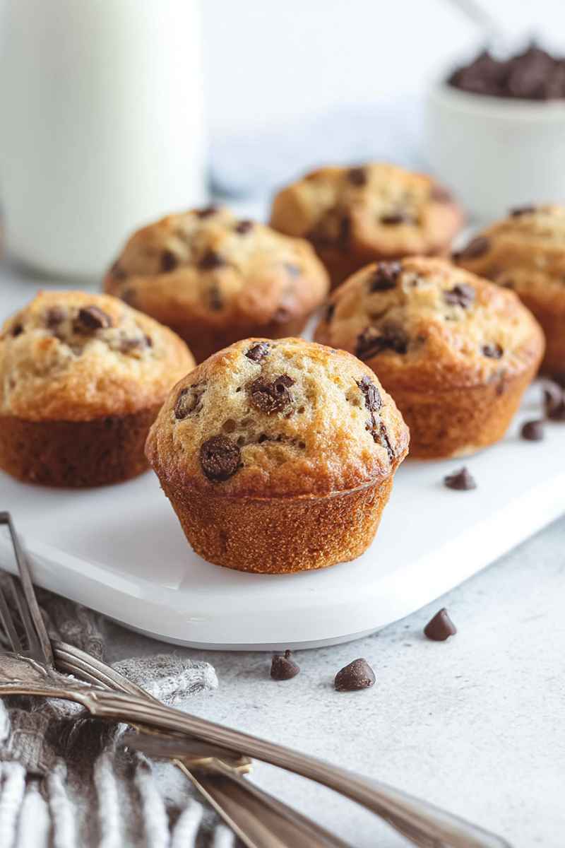 Close-up of light golden-brown mini banana chocolate chip muffins showcasing moist texture and chocolate chips.