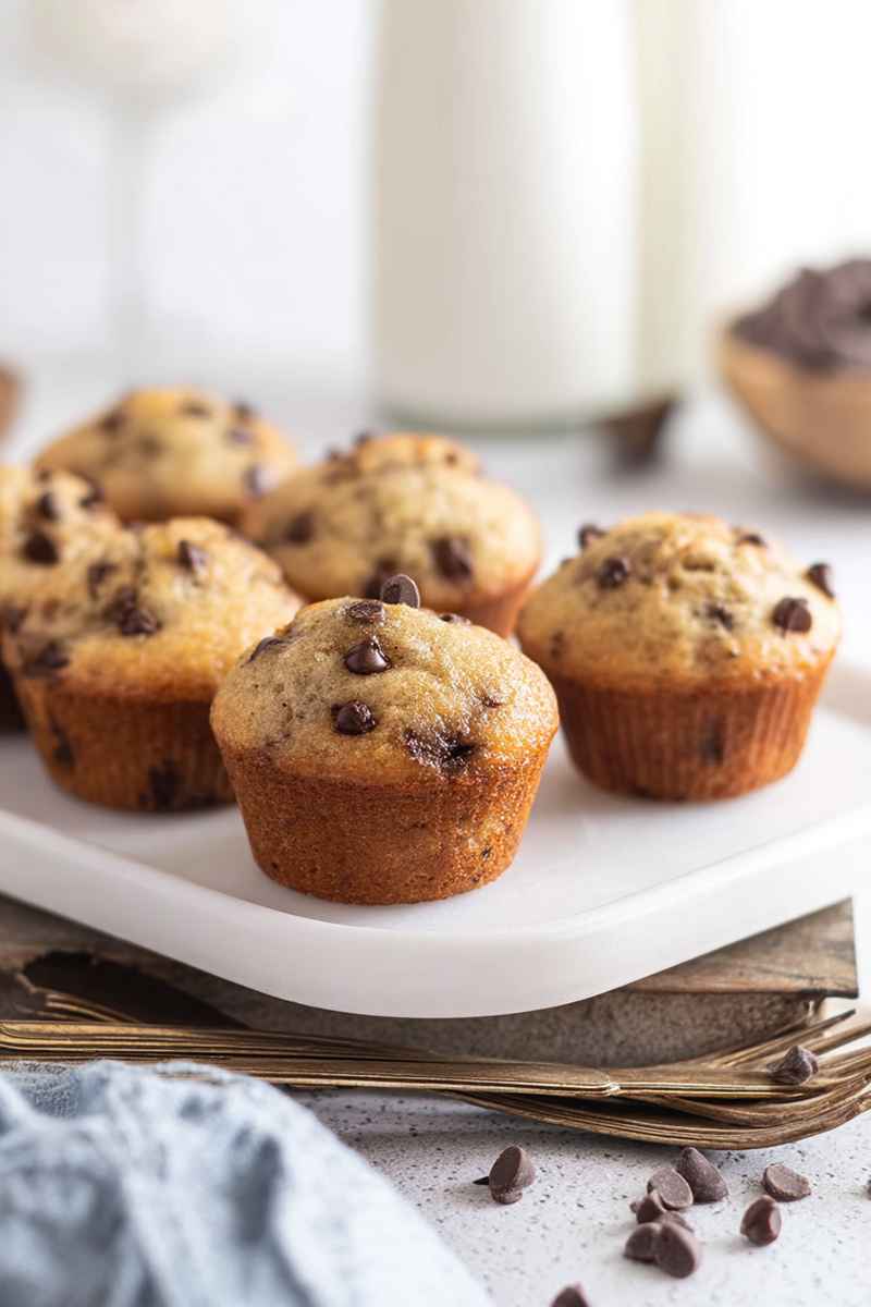 Golden mini banana chocolate chip muffins on a white plate, elegantly presented on a gold-rimmed tray.