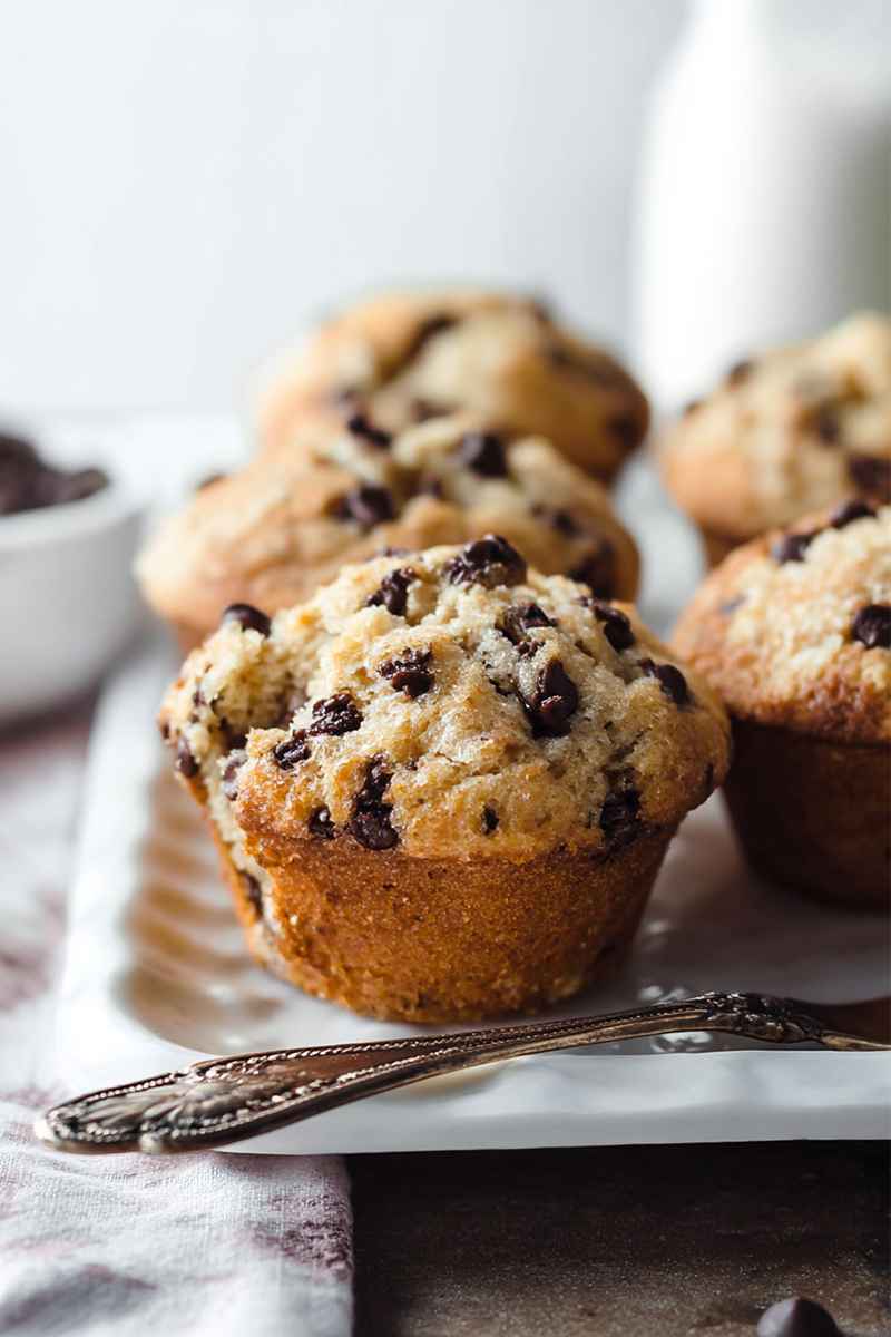 A tray of freshly baked Chocolate Chip Muffins cooling on a wire rack, highlighting their golden crust and visible chocolate chips.