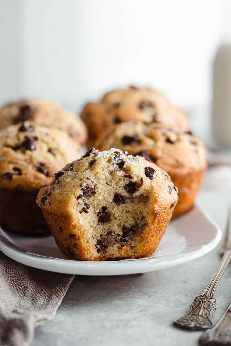 Golden Chocolate Chip Muffins on a white plate, topped with coarse sugar, ready to be enjoyed.