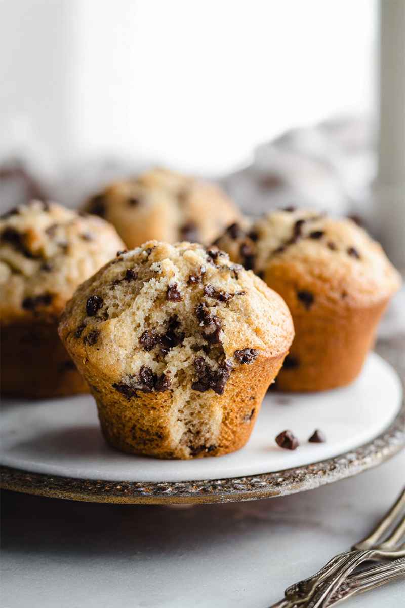 Golden Chocolate Chip Muffins on a white plate, with a few chocolate chips scattered around, ready to be savored.