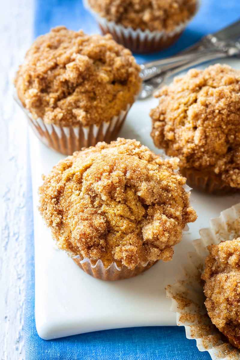 Cluster of golden banana muffins with a cinnamon-sugar crumble topping, served on a white plate.