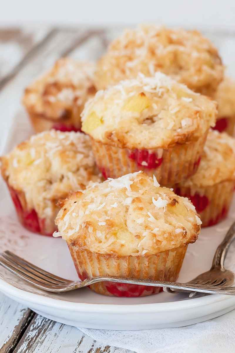 A plate of banana pineapple muffins garnished with coconut shreds and maraschino cherries, ready to be enjoyed.