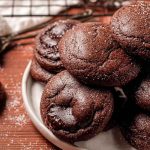 A plate of Chocolate Lava Cookies with a rich, dark chocolate exterior, some dusted with powdered sugar.