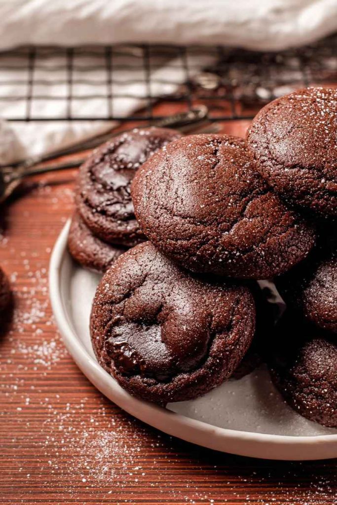 A plate of Chocolate Lava Cookies with a rich, dark chocolate exterior, some dusted with powdered sugar.