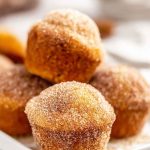 Mini muffins coated in cinnamon sugar, arranged on a white plate.