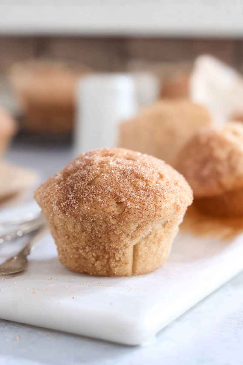 A Cinnamon Sugar Doughnut Muffin dusted with cinnamon sugar, ready to be served with a fork.