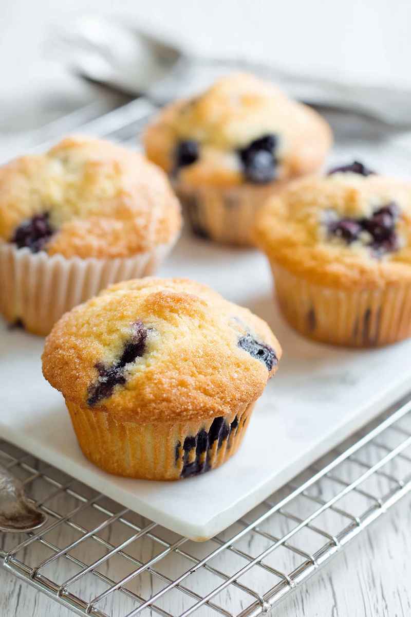 Cluster of golden-blueberry muffins with visible blueberries, cooling on a rack.