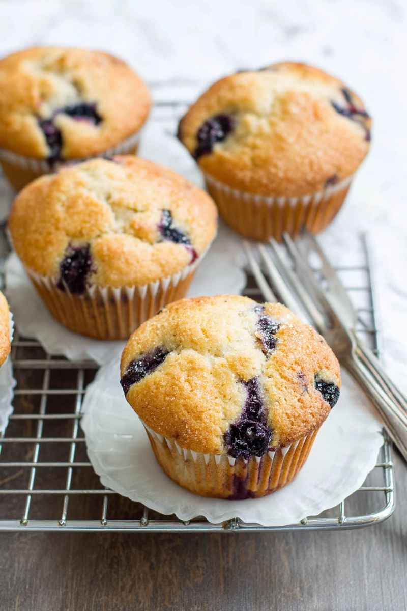 Fluffy blueberry muffins with visible blueberries, cooling on a rack.
