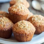 Cluster of golden oatmeal muffins with a crumbly sugar topping, arranged on a white plate.