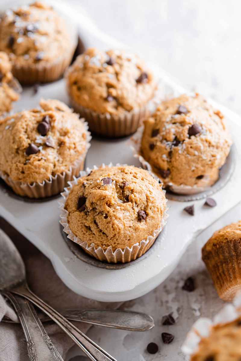 Cluster of golden peanut butter muffins with chocolate chips and sugar, some still in liners.