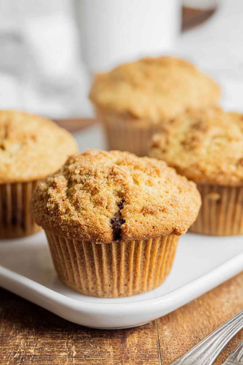 Four cappuccino muffins with chocolate and streusel topping on a white serving plate.