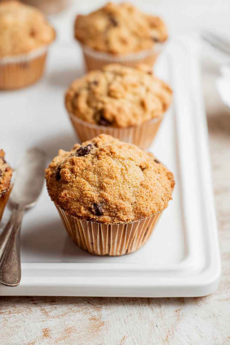 Several baked cappuccino muffins with chocolate chunks and streusel on a white platter.