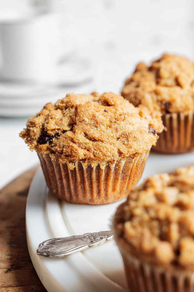 Close-up of a golden cappuccino muffin with chocolate chips and streusel on a white plate.