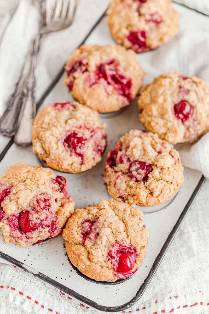 Fluffy cherry cobbler muffins with a crumbly streusel topping, showcasing vibrant red cherries peeking through.