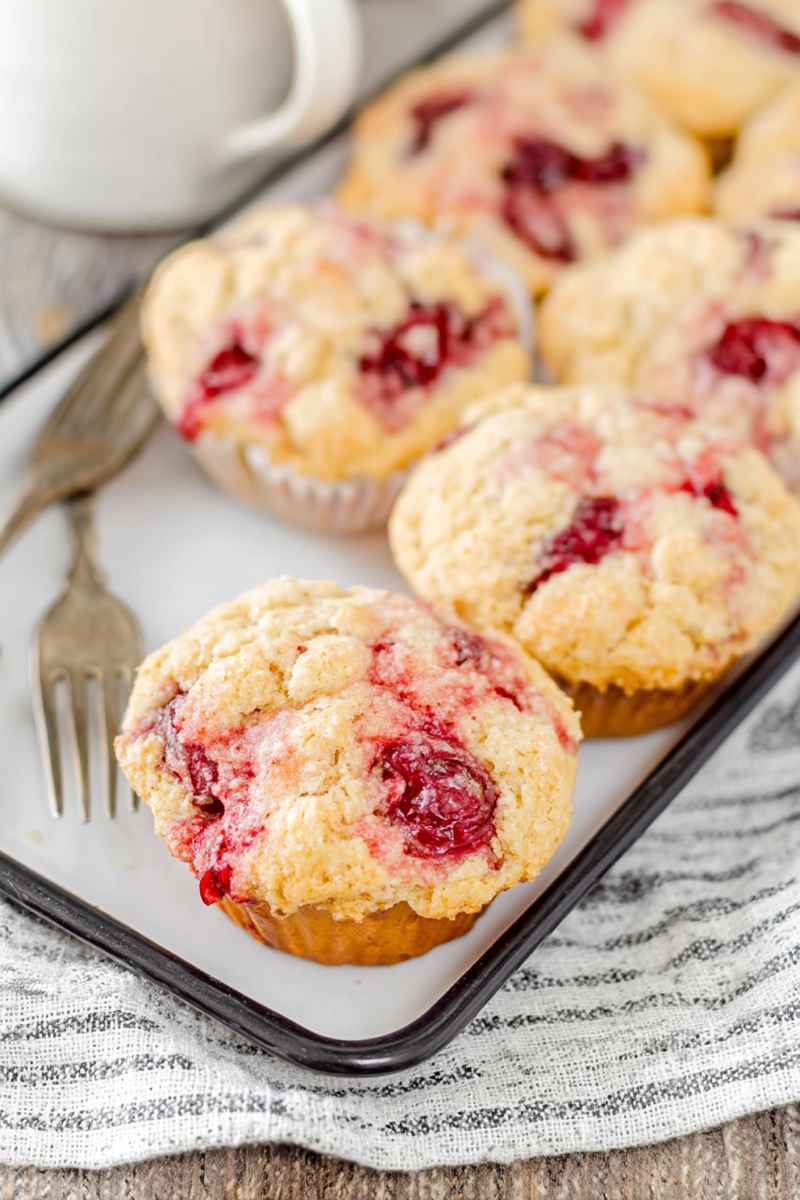 Golden-brown cherry cobbler muffins with a crumbly streusel topping, placed on a white tray.