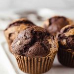 Chocolaty muffins with peanut butter swirls on a white serving tray.