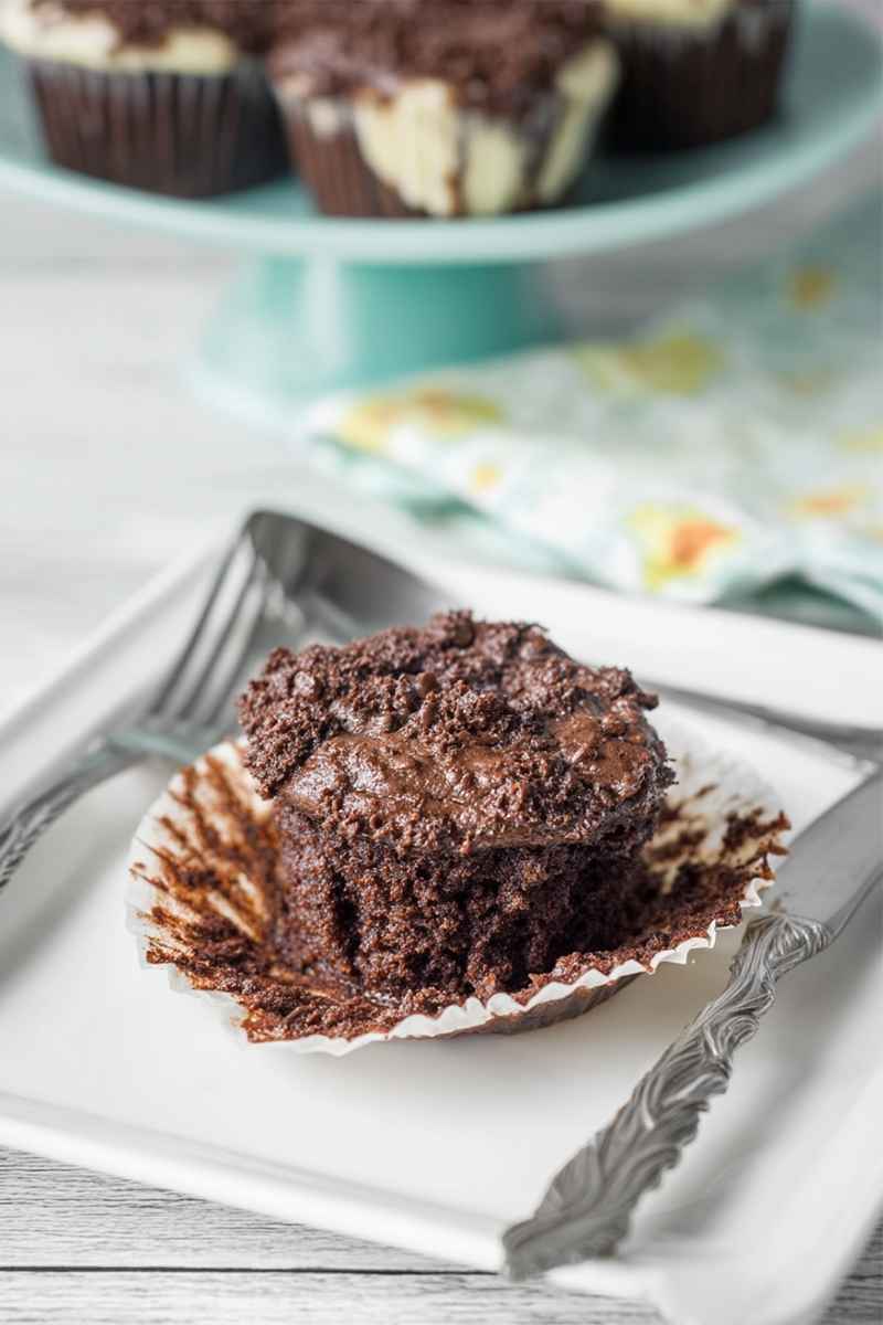 Chocolate muffin with cheesecake filling, presented on a white plate with a fork nearby.