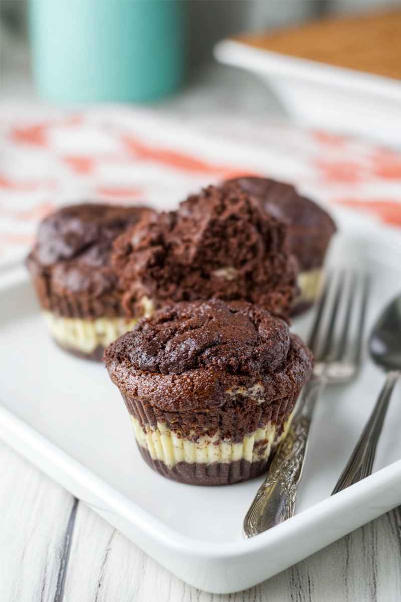 Delicious double chocolate cheesecake muffins with a creamy layer, served on a white plate.