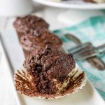 Close-up of chocolate muffins with cheesecake filling, placed on a white plate.