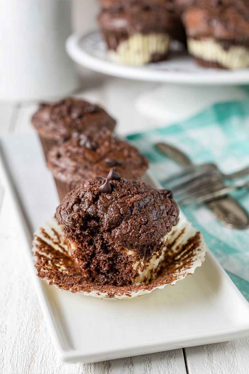 Close-up of chocolate muffins with cheesecake filling, placed on a white plate.