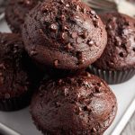 Close-up of freshly baked double chocolate muffins, showcasing their moist texture and chocolate chip topping.