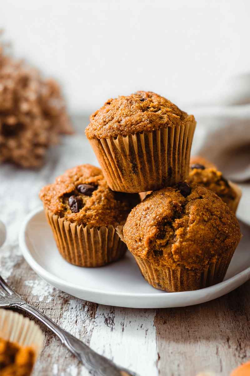 Fluffy pumpkin muffins with chocolate chips, arranged on a rustic wooden table.