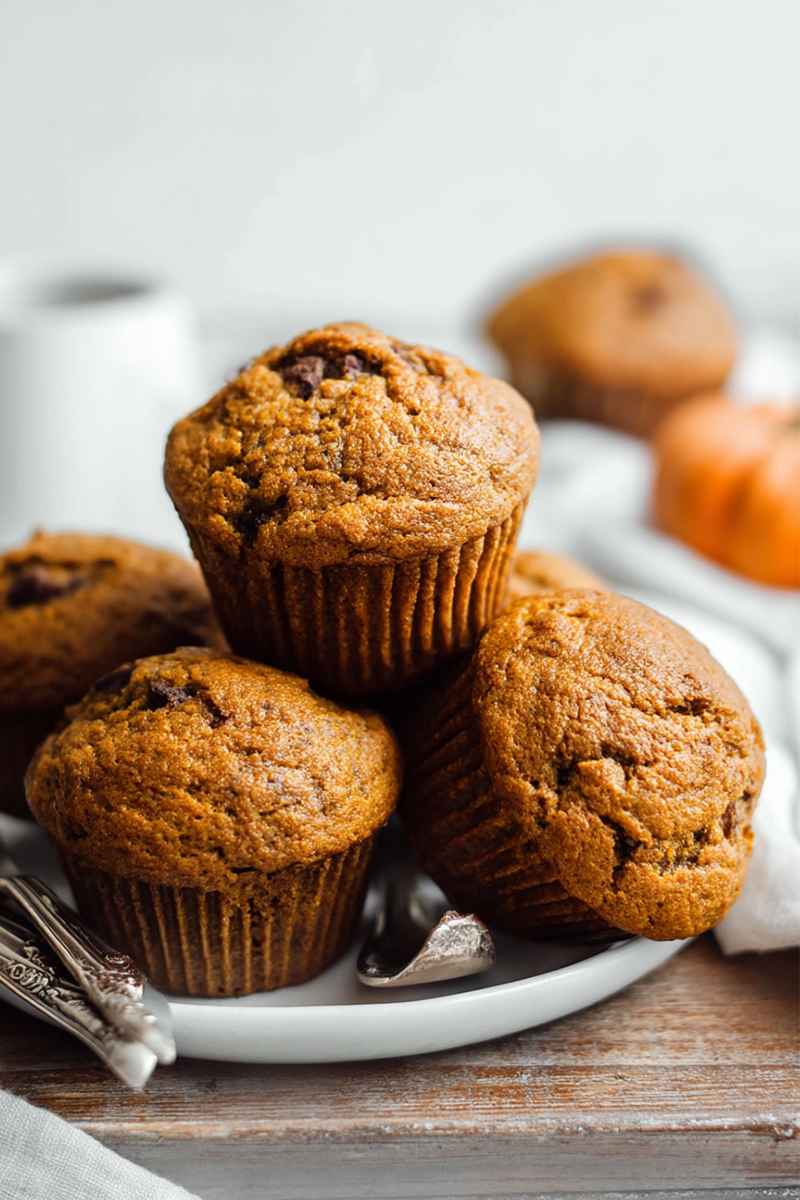 Pumpkin muffins with bakery-style tops, displayed on a plate with a vintage fork.