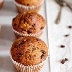 Golden-brown mocha muffins with chocolate chips, displayed on a cooling rack.
