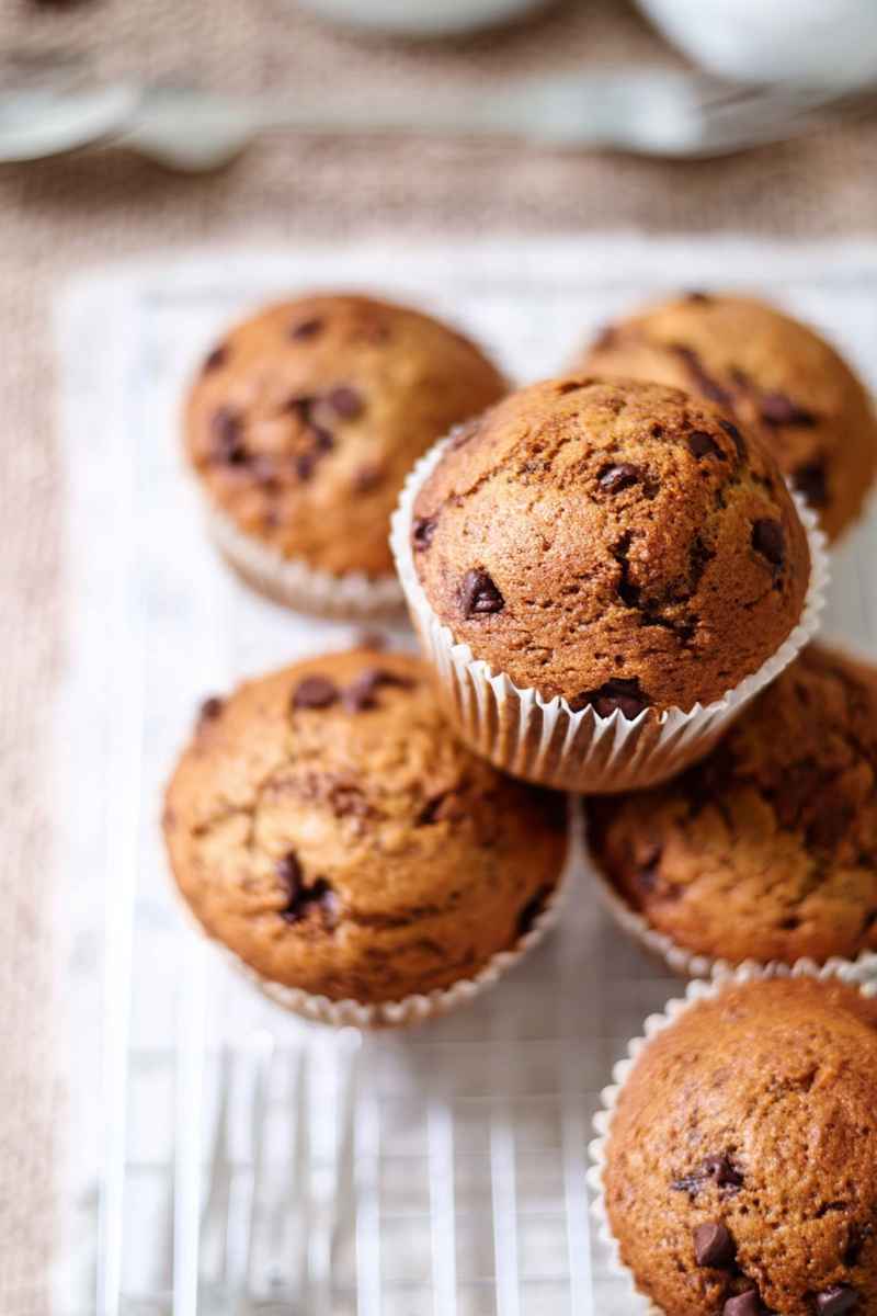 Delicious mocha muffins with chocolate chips, stacked on a white plate.