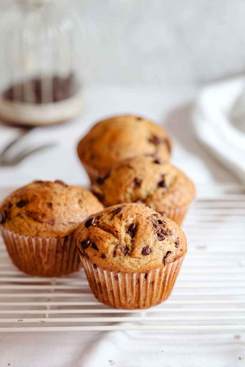Golden mocha muffins with chocolate chips, placed on a cooling rack near a glass of coffee.