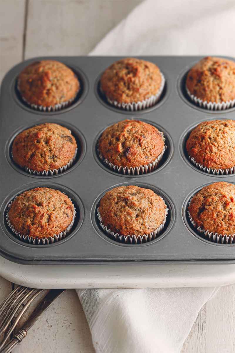 Six perfectly baked carrot muffins in a muffin tin, showcasing their golden tops and moist interiors.