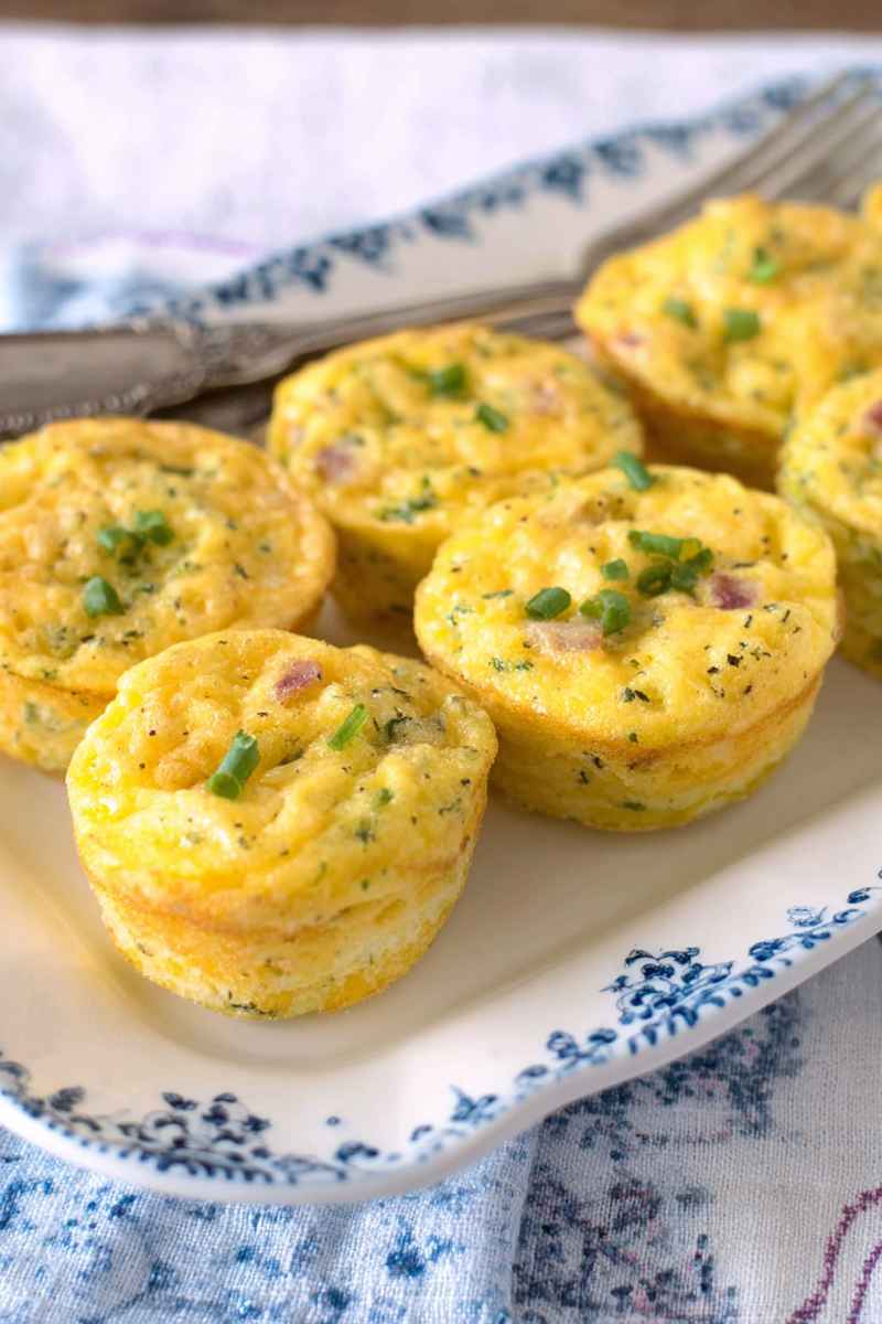 A close-up of fluffy muffin tin omelets garnished with chopped green onions, ready to eat.