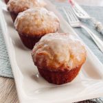 Rows of golden Old Fashioned Donut Muffins with a smooth glaze, served on a white plate.