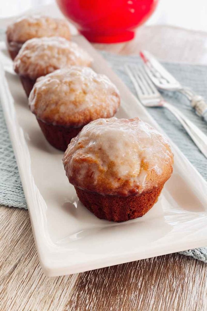 Rows of golden Old Fashioned Donut Muffins with a smooth glaze, served on a white plate.