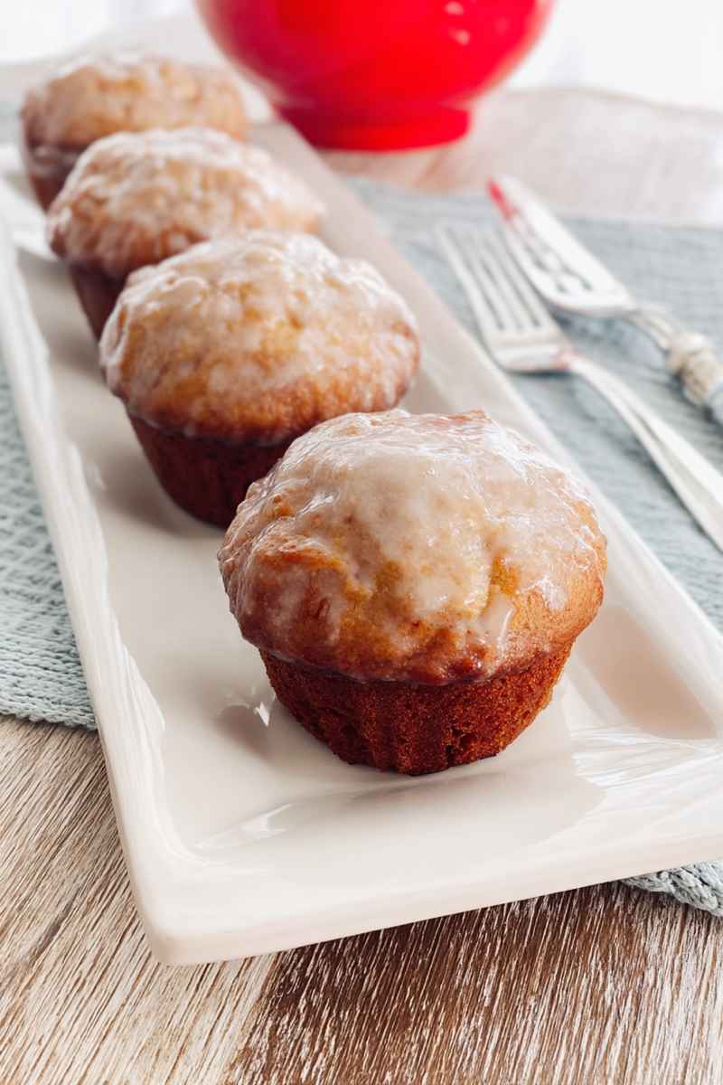 Rows of golden Old Fashioned Donut Muffins with a smooth glaze, served on a white plate.