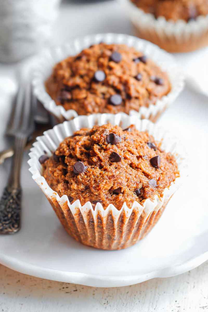 Delicious Paleo Sweet Potato Muffins topped with chocolate chips, served on white paper liners.
