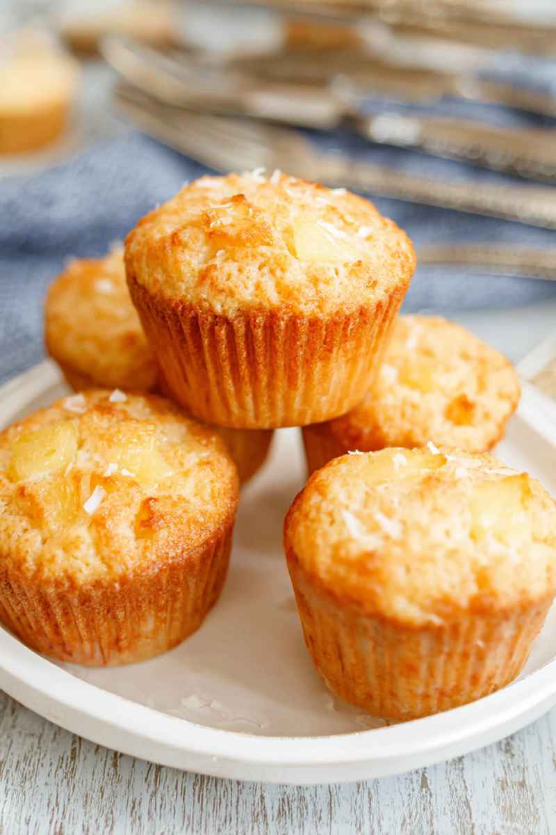 Golden-brown Pina Colada muffins topped with shredded coconut, arranged on a white plate.