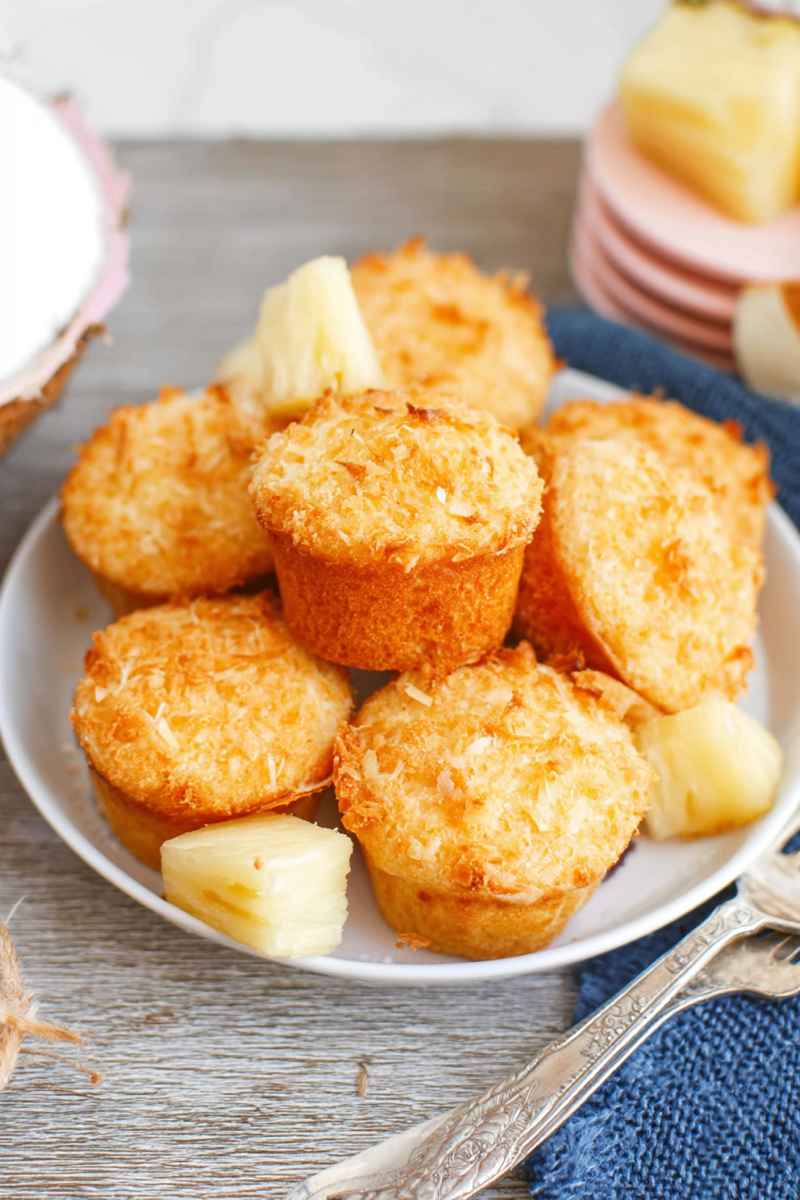 A plate of golden Pina Colada muffins garnished with fresh pineapple slices and coconut flakes.