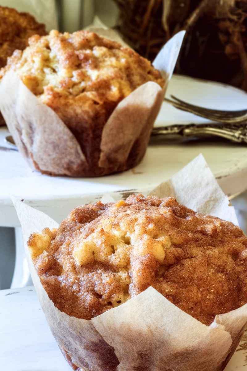 Close-up of a golden apple cinnamon muffin showcasing its tender apple pieces and crunchy topping.