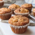 A plate of apple muffins with a crispy cinnamon crumble topping, highlighting their homemade appeal.