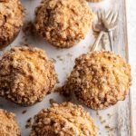 Golden-brown banana walnut streusel muffins with a crumbly topping, arranged on a rustic wooden board.