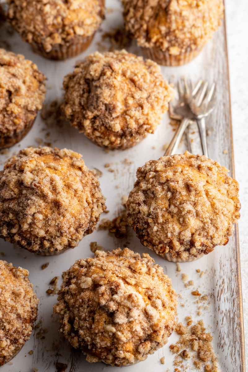 Golden-brown banana walnut streusel muffins with a crumbly topping, arranged on a rustic wooden board.