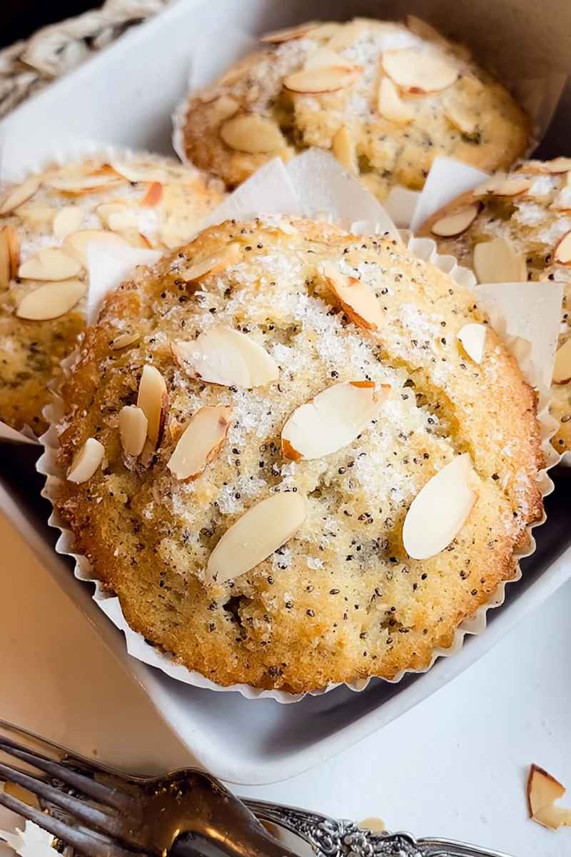 Golden Bakery-Style Muffins with poppy seeds and sliced almonds, ready to serve.