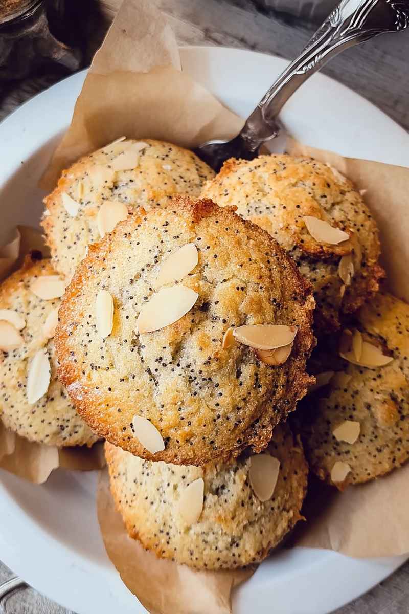Fluffy Almond Poppy Seed Muffins with a sprinkle of sugar and sliced almonds on top.