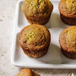 A tray of zucchini muffins with a golden-brown finish, showcasing their moist texture.