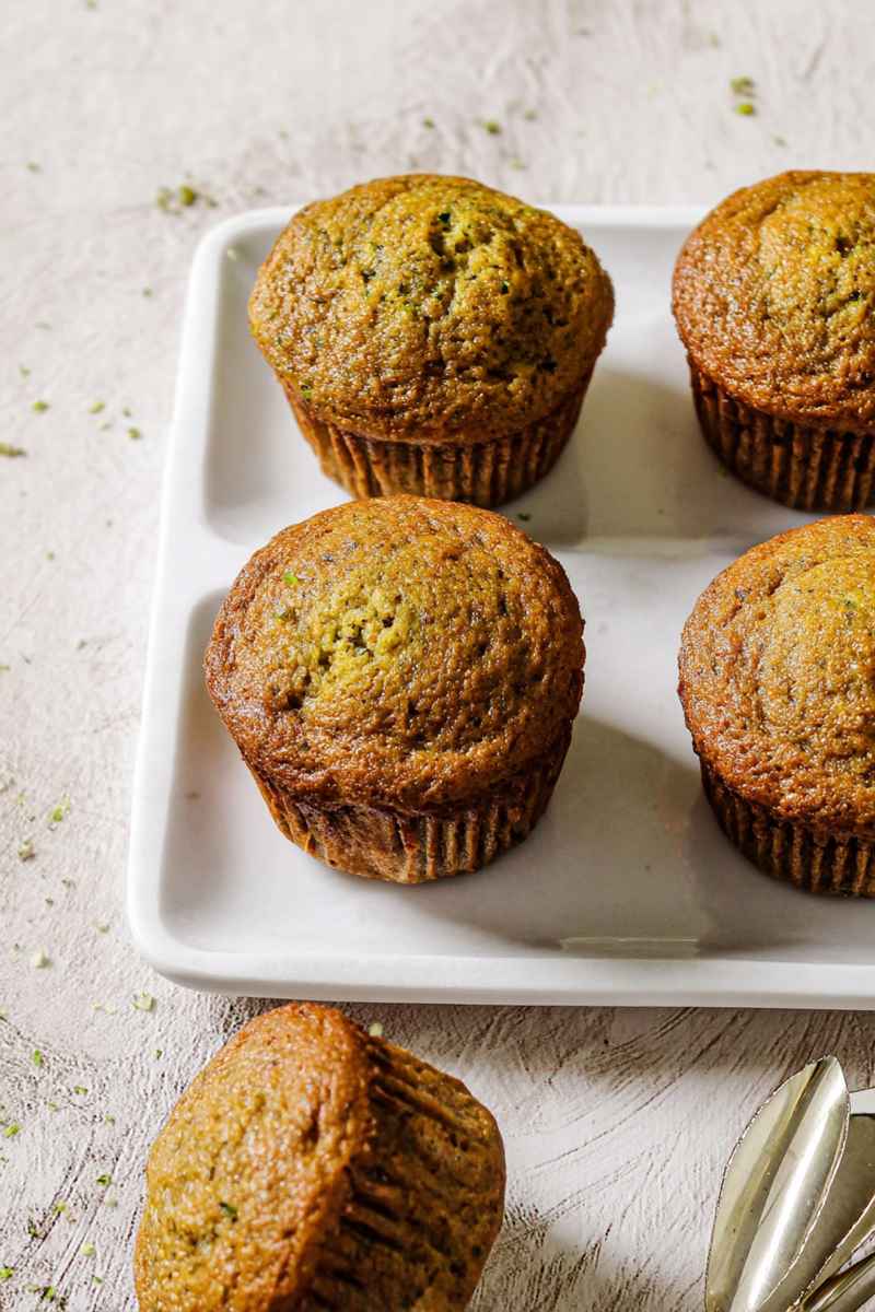 A tray of zucchini muffins with a golden-brown finish, showcasing their moist texture.