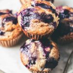 Close-up of Cardamom-Spiced Blueberry Jam Muffins on a white plate, showcasing their fluffy texture and vibrant blueberry filling.