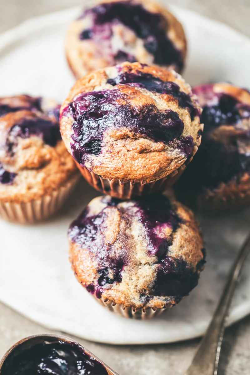Close-up of Cardamom-Spiced Blueberry Jam Muffins on a white plate, showcasing their fluffy texture and vibrant blueberry filling.